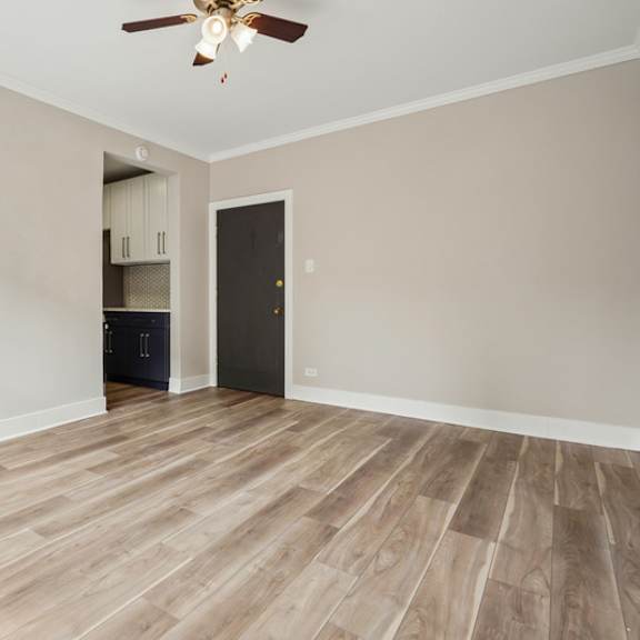 a room with a ceiling fan and wooden flooring.