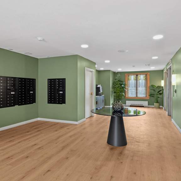 a room with green walls and wooden floors has a black table in the middle.