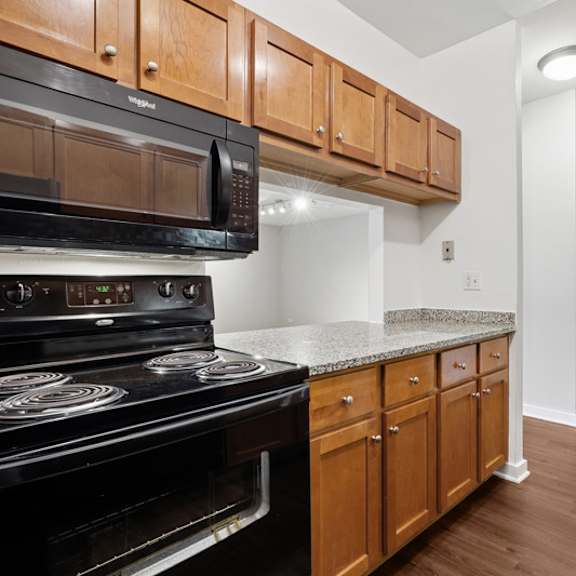 a black microwave oven is mounted above a black stove with a silver handle.