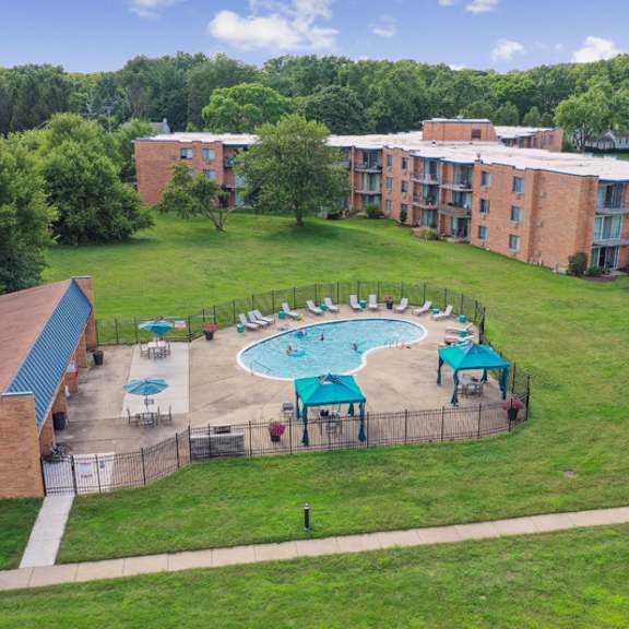 a swimming pool surrounded by a grassy area and apartment buildings.