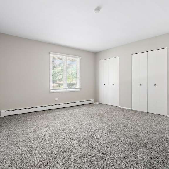a room with grey carpet and white cupboards.
