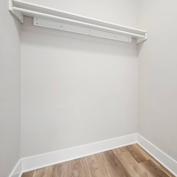 a white wall with a white shelf and a wooden floor.