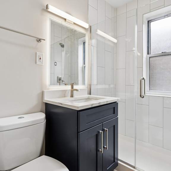 a bathroom with a white toilet, a sink, and a window.