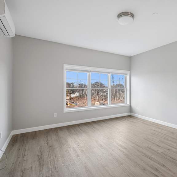 a room with a large window and wooden flooring.