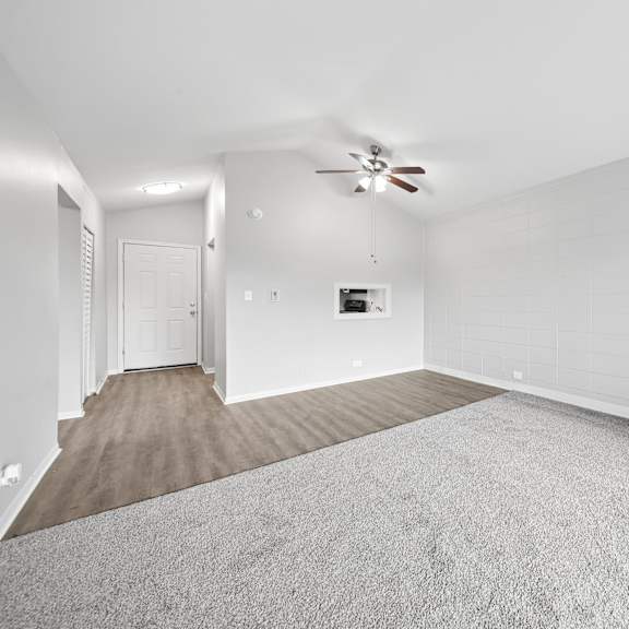 a spacious room with a carpeted floor and a ceiling fan.