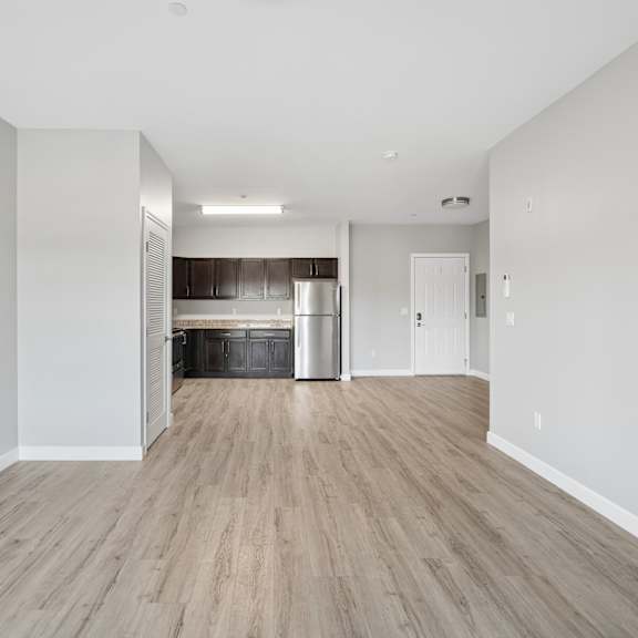 a spacious room with wooden flooring and white walls.