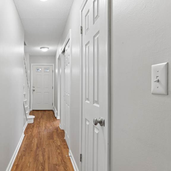 a long hallway with white doors and wood floors.