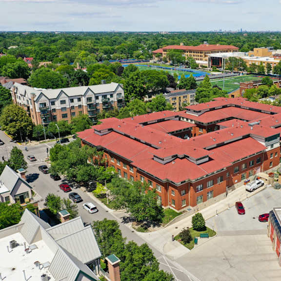 a large red building with a red roof is surrounded by trees and other buildings.