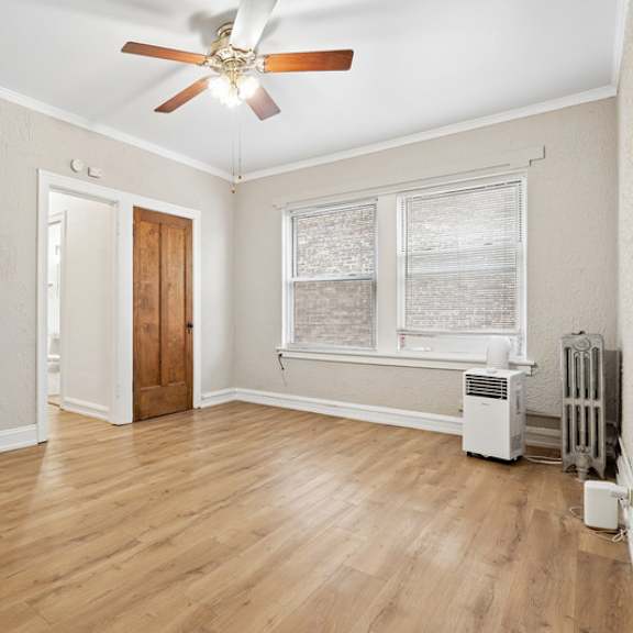 a room with a ceiling fan and a window with blinds.