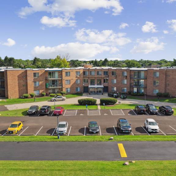a parking lot in front of a multi-story brick building.