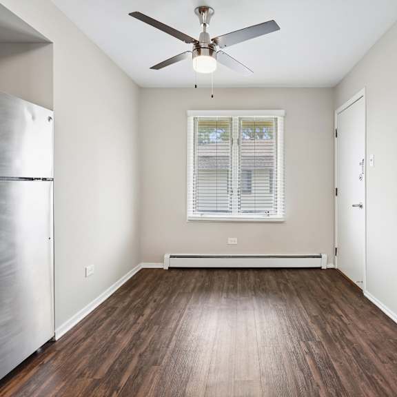 a room with a stainless steel refrigerator and wooden flooring.