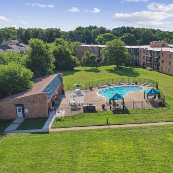 a swimming pool is surrounded by a fence and chairs in a grassy area.