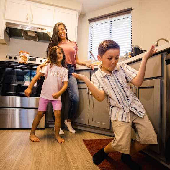 a woman and two children standing in a kitchen
