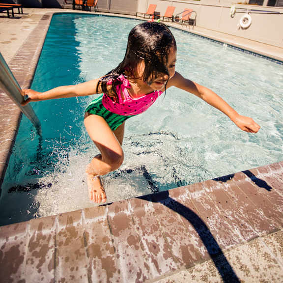 a little girl jumping into a swimming pool