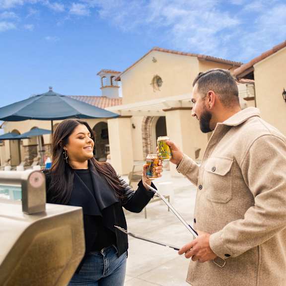 a man giving a woman a bottle of beer outside of a house