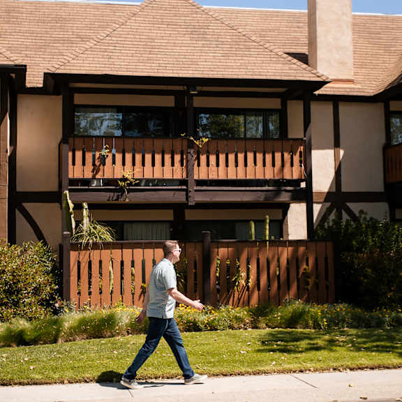 a man walks past a house with a wooden fence at oak park apartments, california