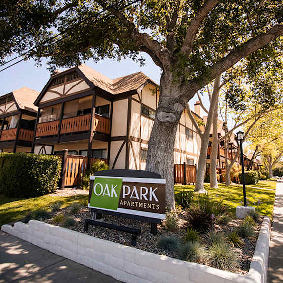 a sign for oak park apartments in front of a tree at oak park apartments, solvang, 93463