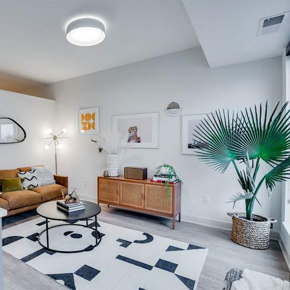 a living room with a white couch, a coffee table, and a plant. at sora apartments, minneapolis 55415