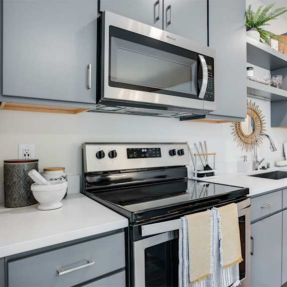 a modern kitchen with a stove, microwave, and refrigerator. at sora apartments, minneapolis, mn, 55415