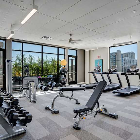 a gym with treadmills, dumbbells, and exercise equipment at sora apartments, minnesota