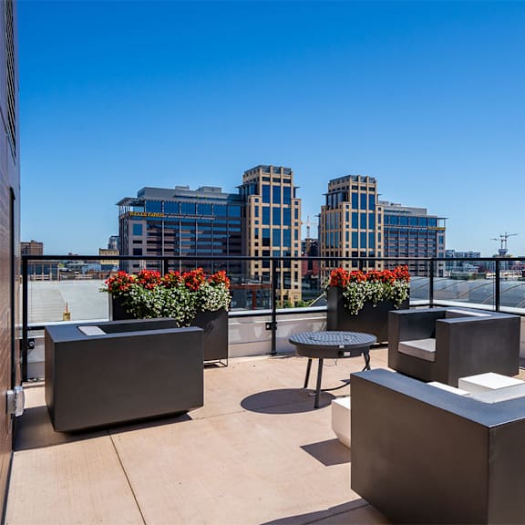 a rooftop patio with a table and chairs overlooking a city skyline at sora apartments, minneapolis 55415