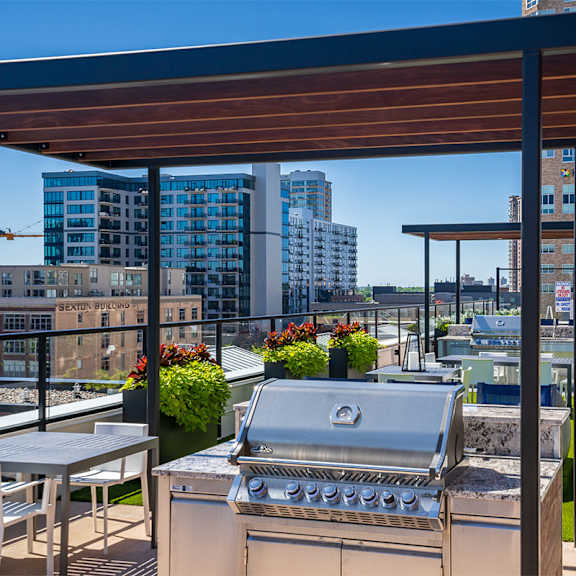 a barbecue grill on a patio with a table and chairs at sora apartments, minnesota