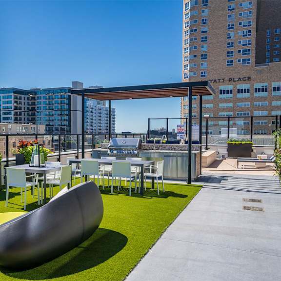 a modern outdoor seating area with a curved bench and a table with chairs. at sora apartments, minneapolis