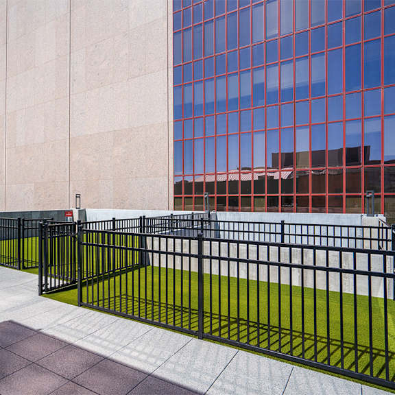 a black metal fence with a green lawn in front of a building. at sora apartments, minneapolis, mn