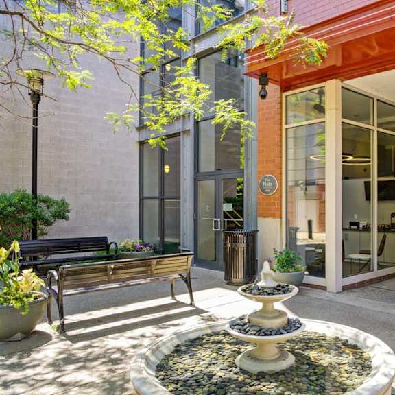a courtyard with a fountain and a bench in front of a building at flats at southside, pittsburgh, pa