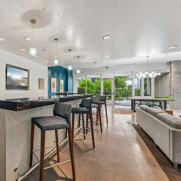 a modern bar area with a white counter and black stools.