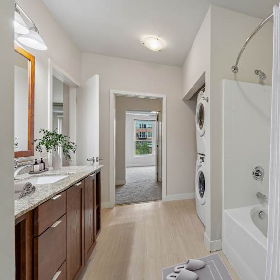 a bathroom with a white tub and a washing machine in the background.