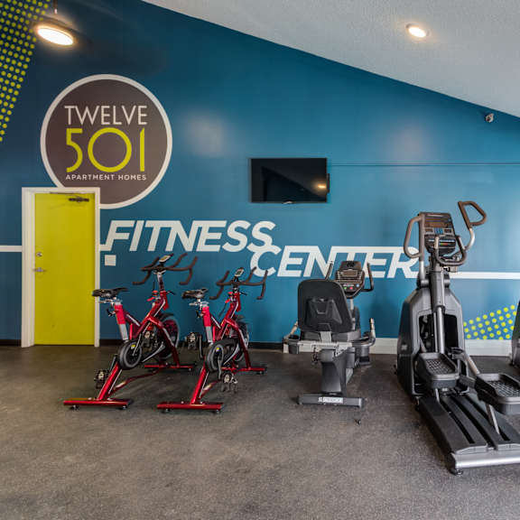 a gym with cardio equipment and a fitness center sign on the wall