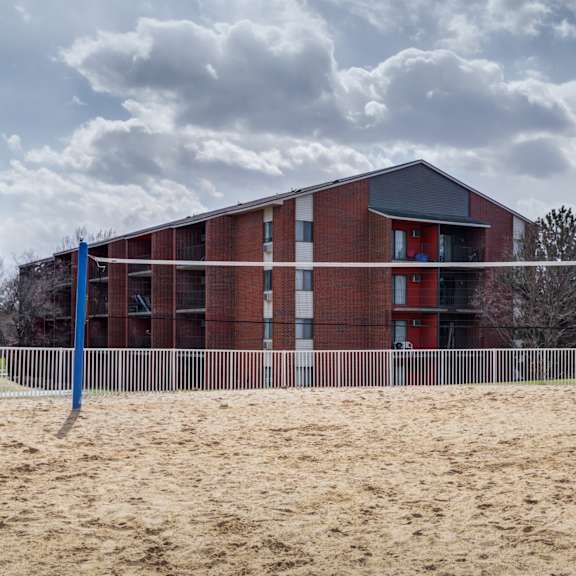 a building on a beach with a volleyball court in front of it