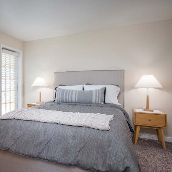 a bedroom with a bed and two lamps and a window at sundial apartments, oregon