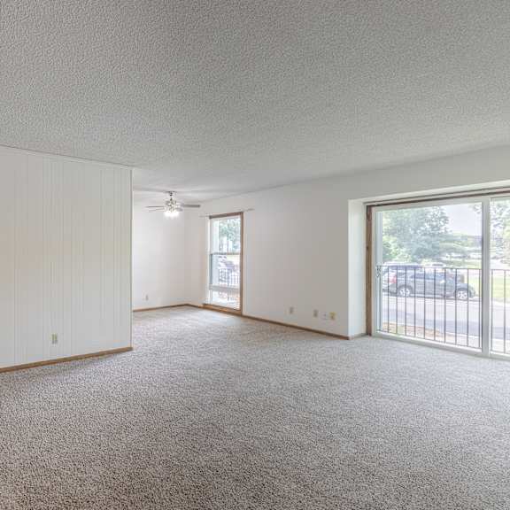 a spacious living room with a sliding glass door leading to a balcony.