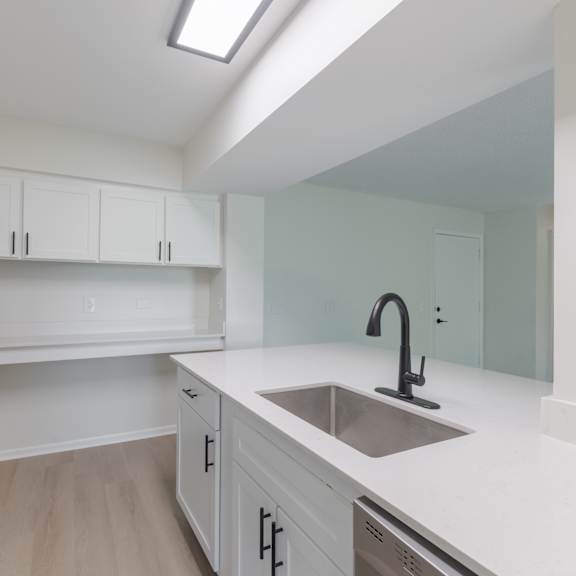 a kitchen with white cabinets and a stainless steel sink.