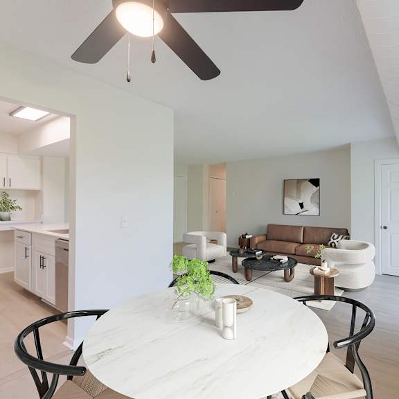 an eating area with a white table and chairs, view of the kitchen and living room