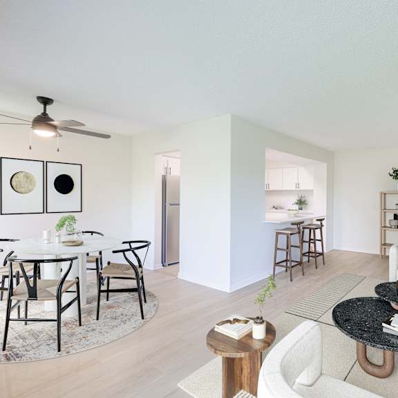 a living room with a white couch, a black coffee table, and a dining table with chairs.