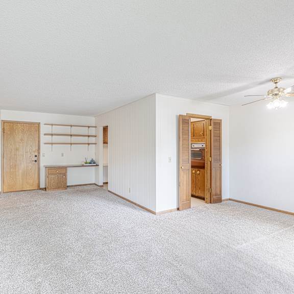 a spacious room with a ceiling fan and a white carpet.