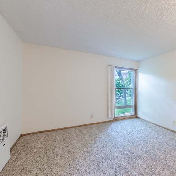 a room with a carpeted floor and a sliding glass door leading to a backyard.