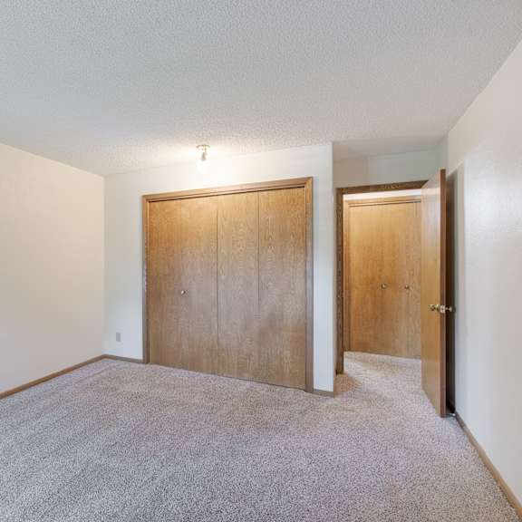 a room with a carpeted floor and two wooden doors.