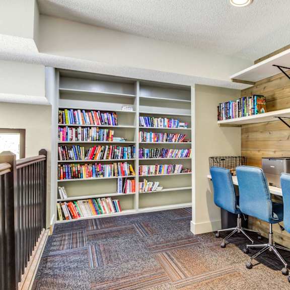 a library with a computer desk and three blue chairs