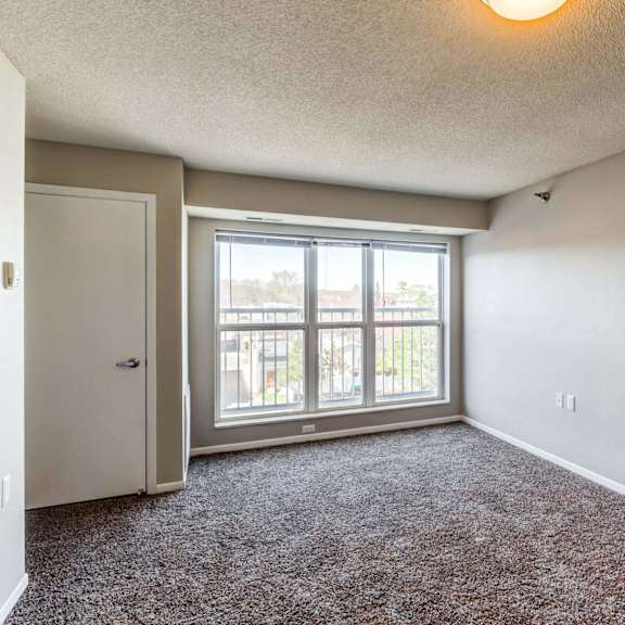 a bedroom with a large window and carpeted flooring