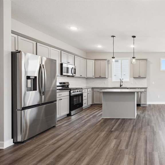 a modern kitchen with stainless steel appliances and wooden flooring.