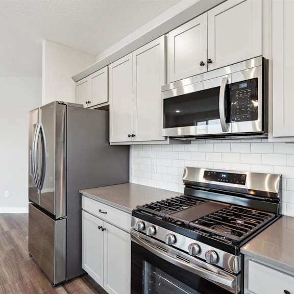a modern kitchen with stainless steel appliances and white cabinets.
