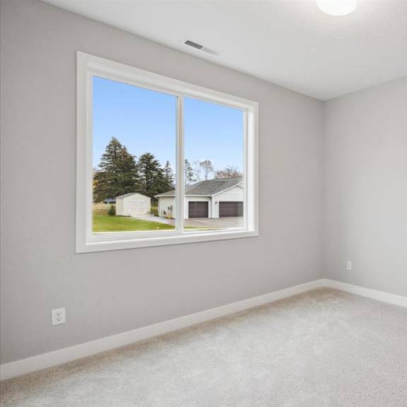 a room with a window showing a view of a house and trees outside.