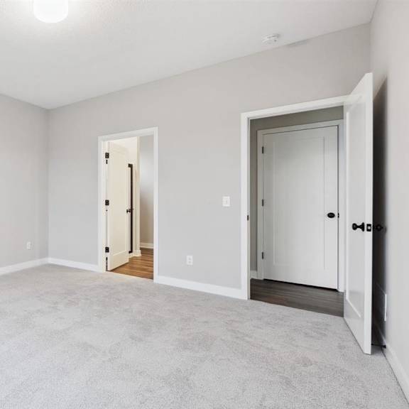 a room with a carpeted floor and two doors.