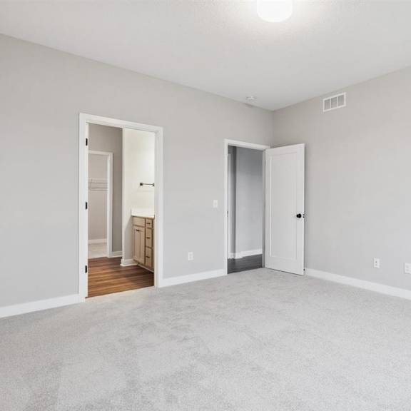 a large empty room with a carpeted floor and two doors.
