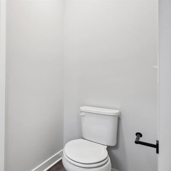 a white toilet in a small bathroom with a white wall and a white floor.