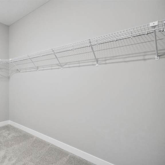 empty room with a carpeted floor and a metal rack on the wall.